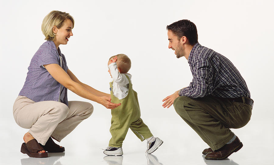 Young Caucasian Couple Kneel With Baby In Overalls Who Walks Towards The Mom Photograph by Photodisc