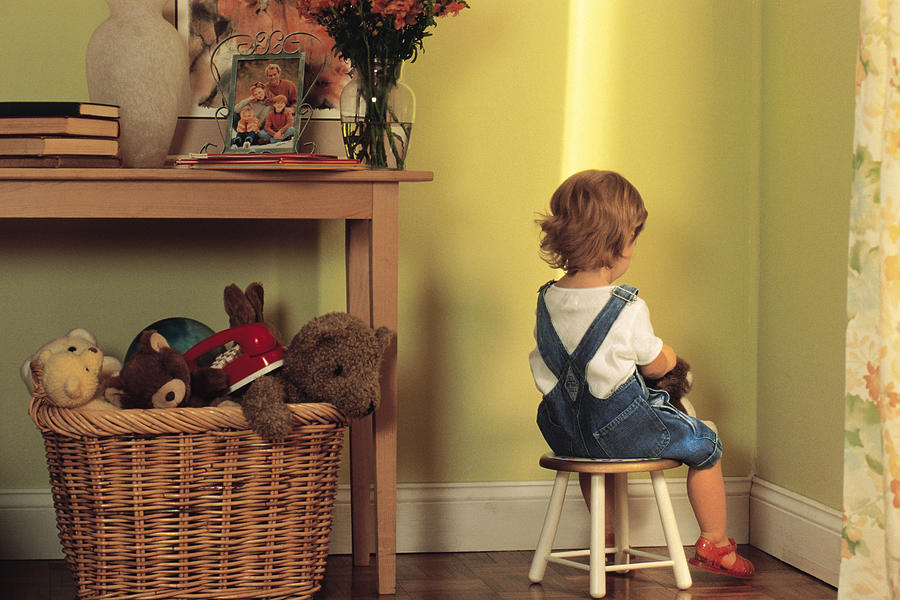 Young child sitting in corner as punishment Photograph by Comstock