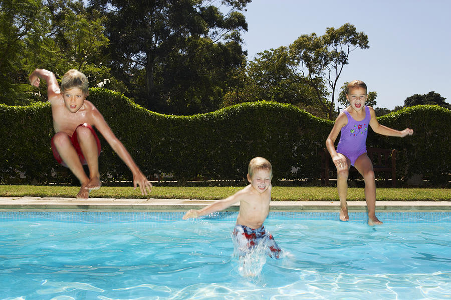 Young Children Jumping into a Swimming Pool Photograph by Digital Vision.