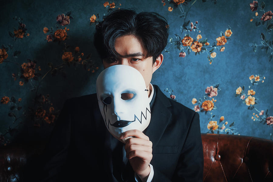 Young Chinese man holding a mask portrait Photograph by Philippe Lejeanvre