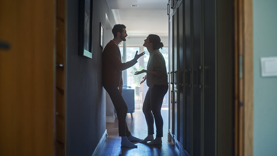 Young Couple Arguing and Fighting. Domestic Violence Scene of Emotional abuse, Stressed Woman and aggressive Man Having Almost Violent Argument in a Dark Claustrophobic Hallway of Apartment. Photograph by Gorodenkoff