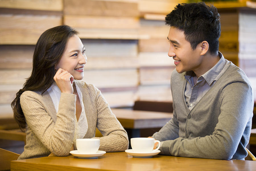 Young couple chatting in cafe Photograph by BJI / Blue Jean Images