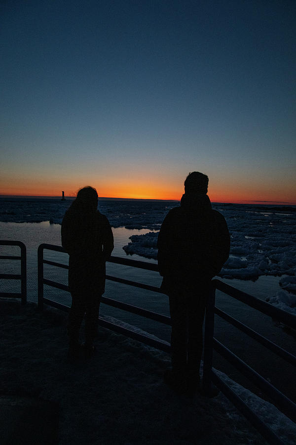 Young couple enjoying sunset over Lake Michigan during winter in Holland Michigan Photograph by Eldon McGraw