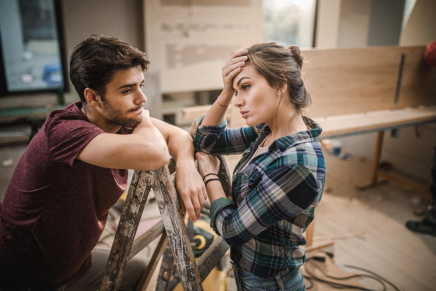 Young couple having problems while renovating their apartment. Photograph by Skynesher