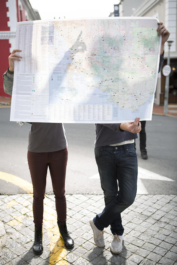 Young couple hiding behind a city map Photograph by Westend61