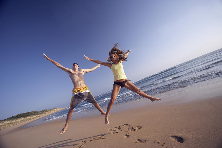 Young Couple Jumping on a Beach Photograph by James Lauritz