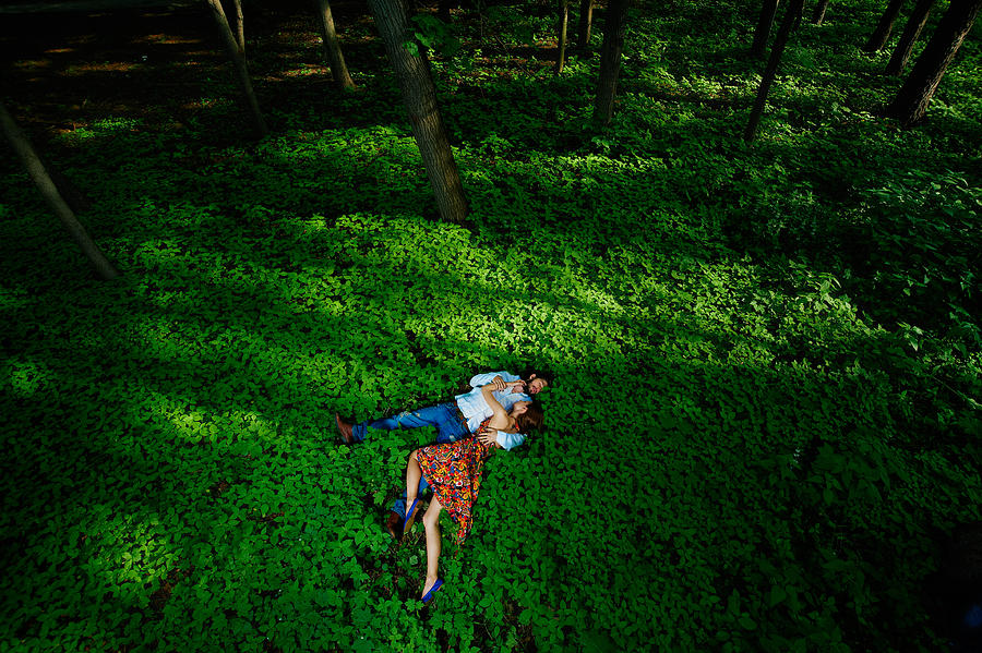 Young couple laying in green forest Photograph by Roman Makhmutov