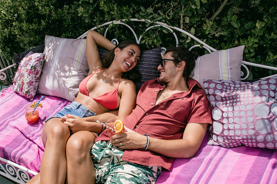 Young couple lounging in the sun on an outdoor sofa Photograph by Hello World