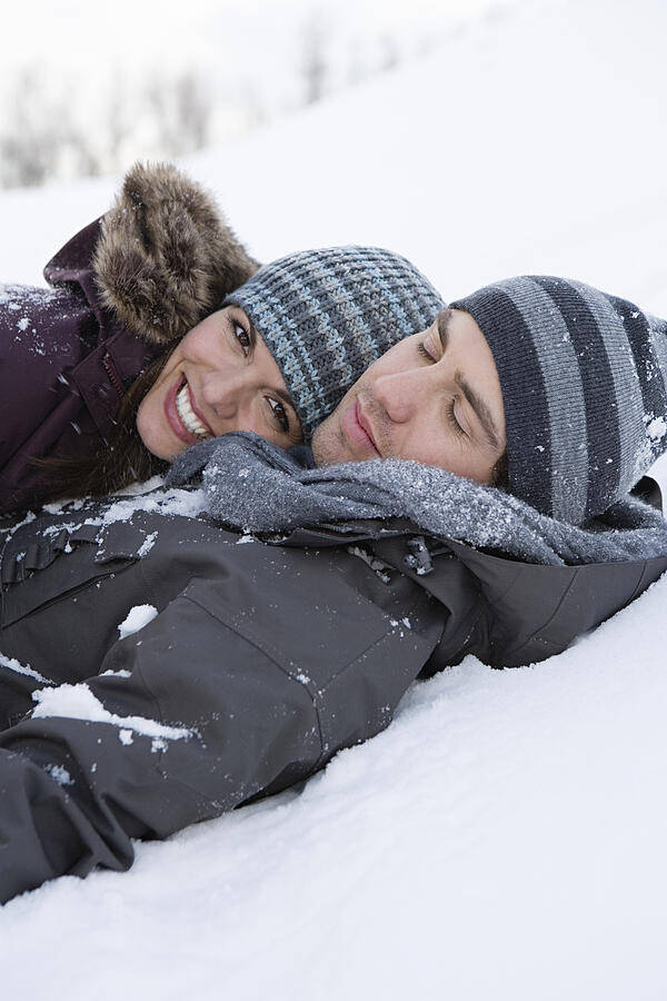 Young couple lying in snow Photograph by Image Source