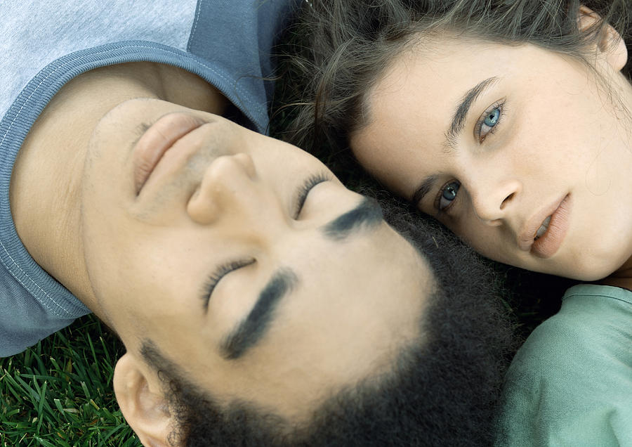 Young couple lying on grass together, close-up Photograph by Odilon Dimier