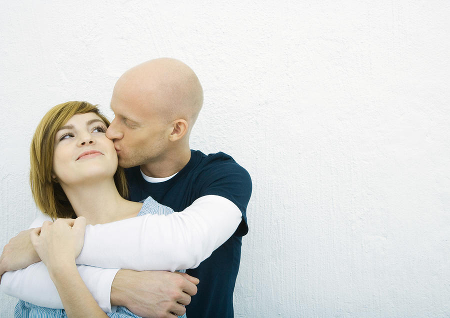 Young couple, man kissing womans cheek woman from behind Photograph by PhotoAlto/Sigrid Olsson