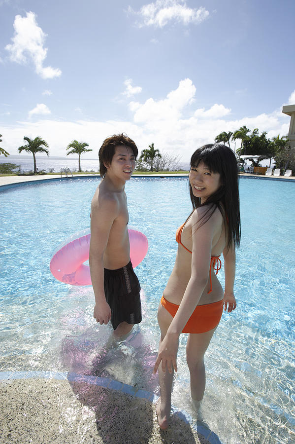 Young Couple Poolside, Man Holding an Inflatable Ring Photograph by Dex