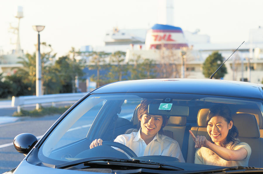 Young couple smiling in car, looking away Photograph by Hitoshi Nishimura