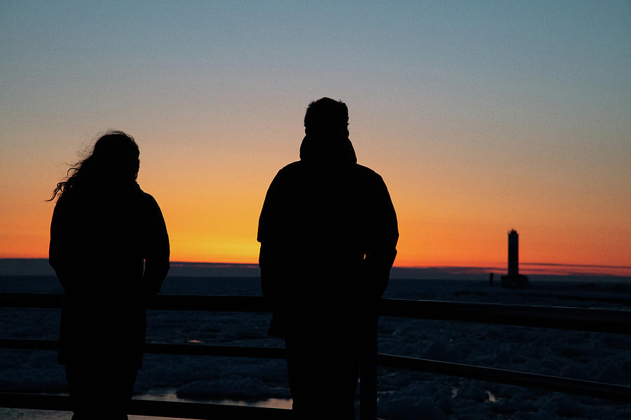 Young couple watching the winter sunset over Lake Michigan on the Holland Michigan Pier Photograph by Eldon McGraw