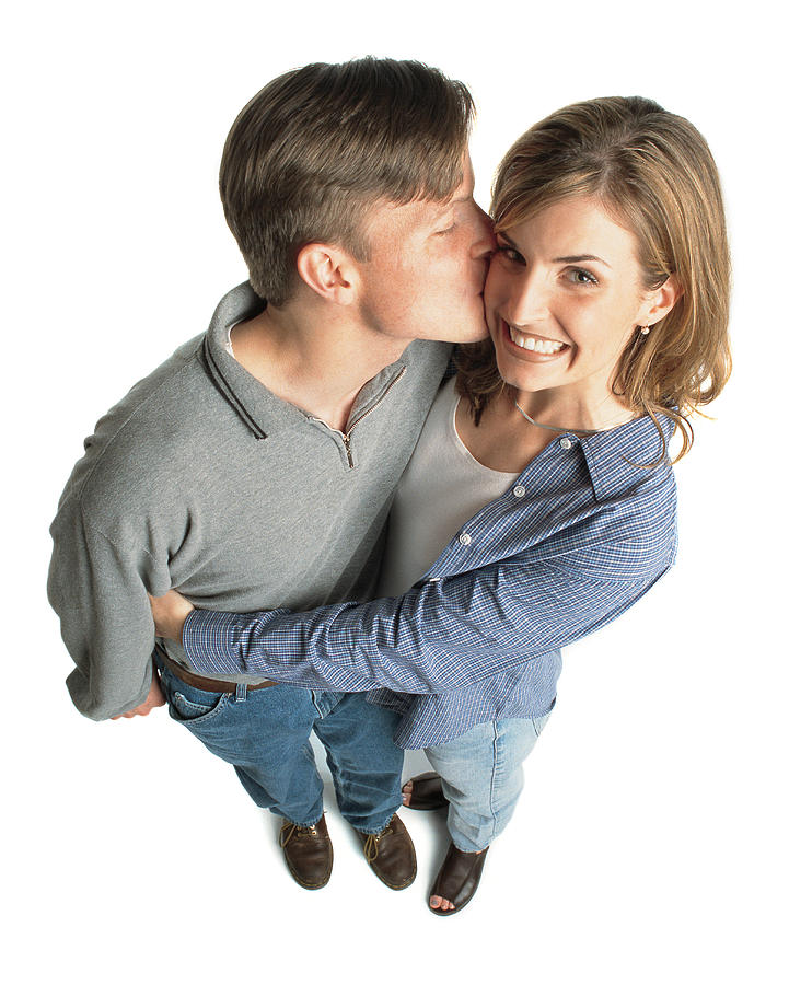 Young Couple With Brown Hair With The Boy Kissing The Girl On The Cheek And She Is Excited And Smiles Photograph by Photodisc