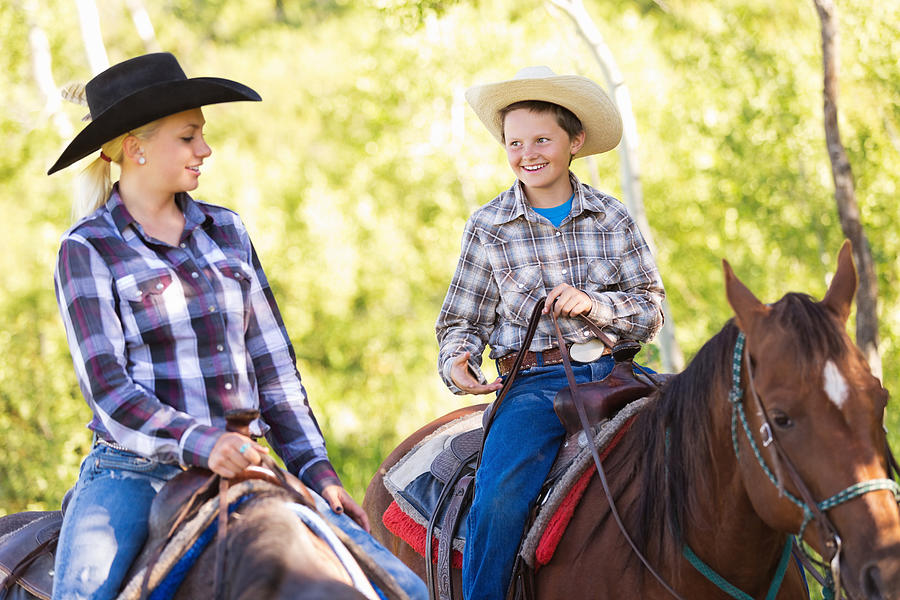 Young cowboy and cowgirl riding horses during trail ride Photograph by SDI Productions