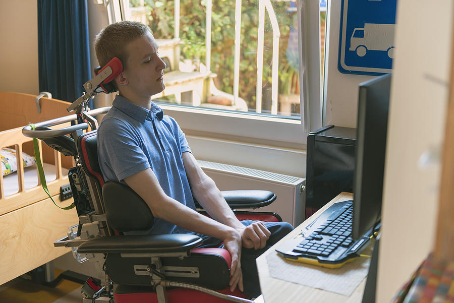 Young disabled man playing computer game Photograph by Funky-data