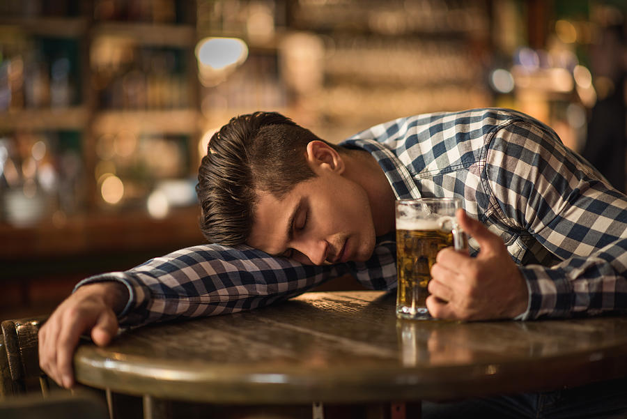 Young drunk man sleeping on the table in a bar. Photograph by Skynesher