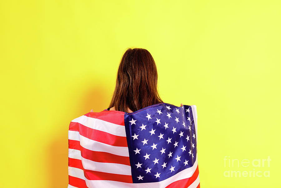 Young embarrassed woman covers herself with an American flag to  Photograph by Joaquin Corbalan