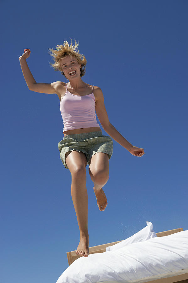 Young Energetic Woman Outdoors Jumping Out of Bed Photograph by Digital Vision.