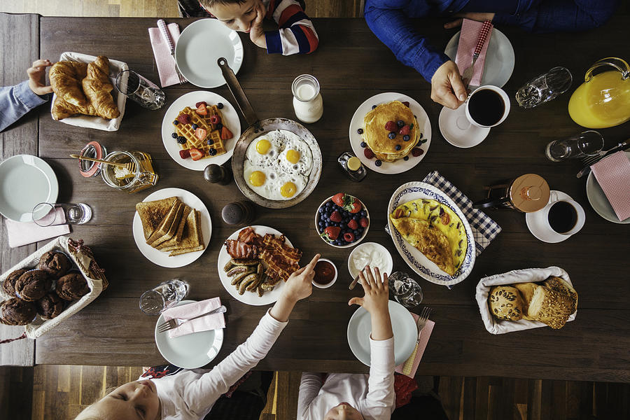 Young Family Having Breakfast with Eggs, Bacon, Yogurt with Fresh Fruits Photograph by GMVozd