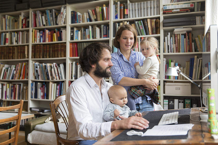 Young family with two children in home office Photograph by Simon Ritzmann