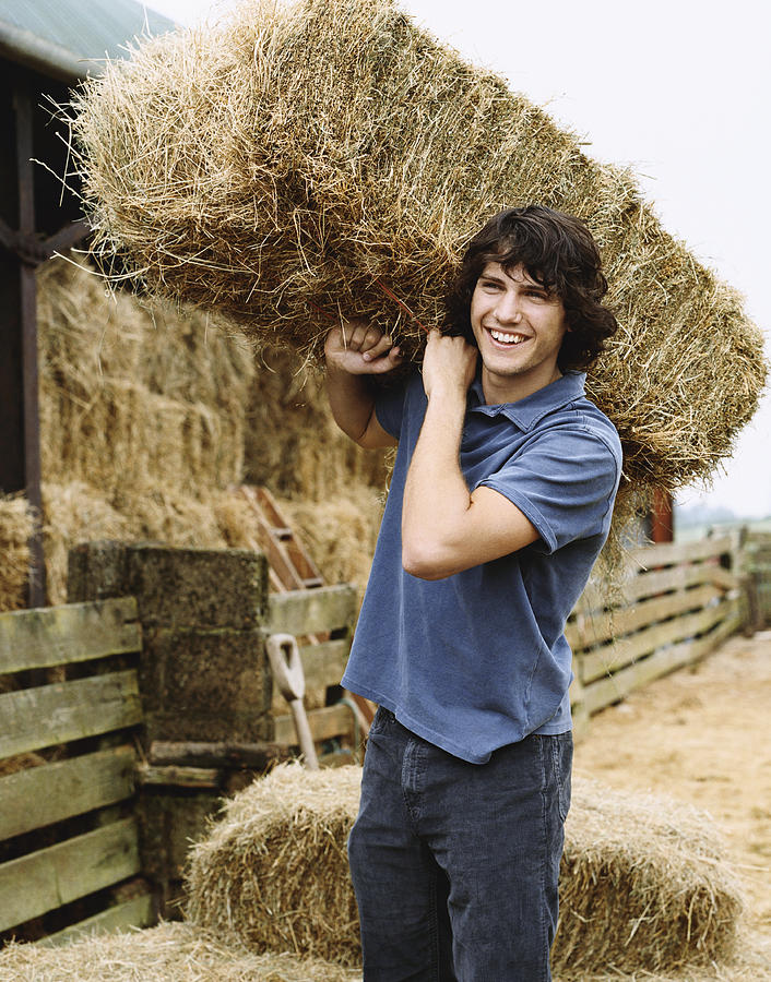 Young Farmer Carrying a Bale of Hay Photograph by Digital Vision.