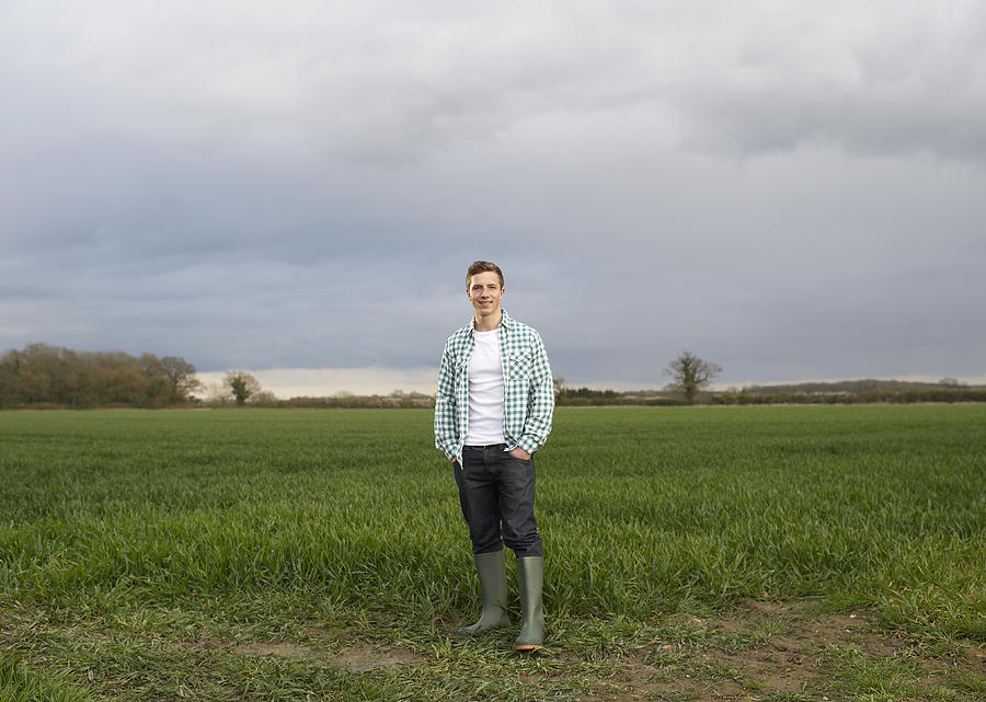 Young farmer standing at edge of field. Photograph by Dougal Waters