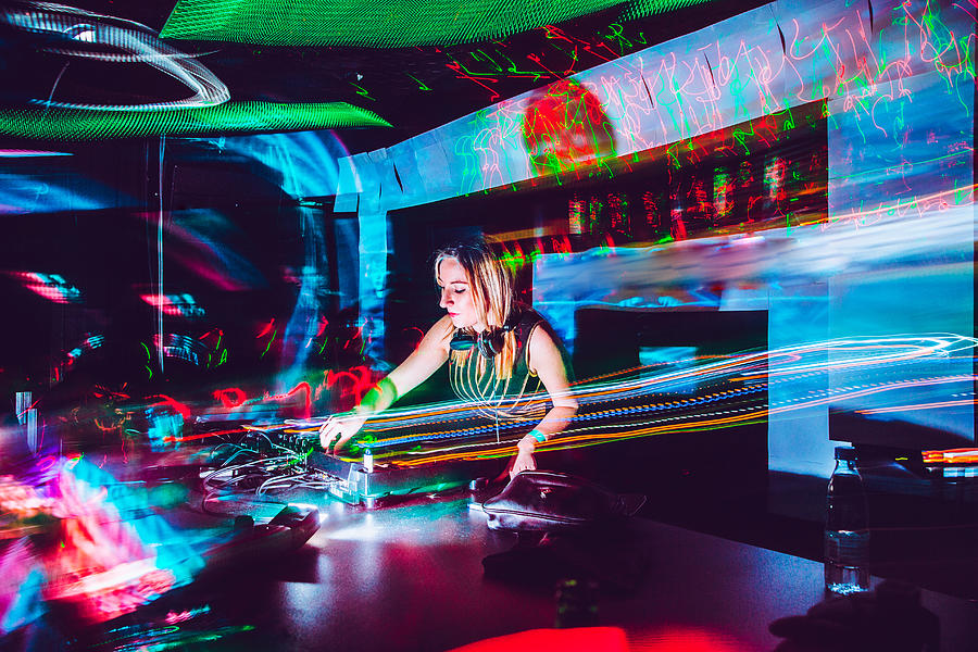 Young Female DJ Mixing Music in a Nightclub Photograph by CasarsaGuru