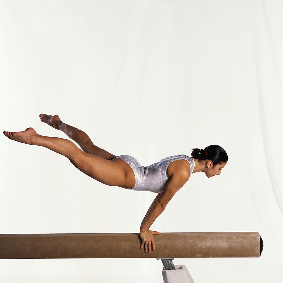 Young female gymnast performing routine on balance beam, side view. Photograph by Dominique Douieb
