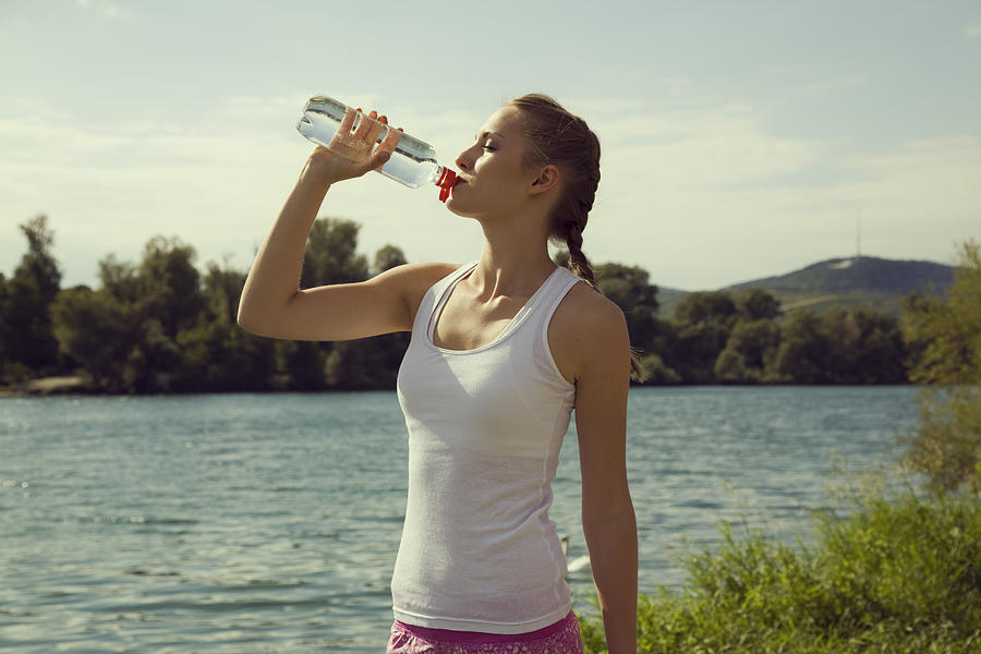 Young female jogger drinking bottled water Photograph by Manuela
