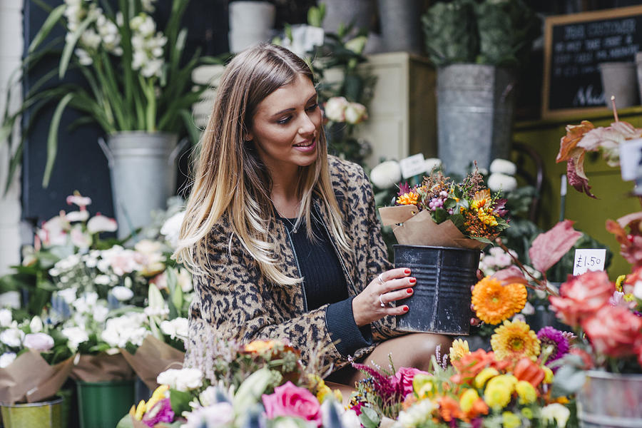Young female life coach and fashion blogger in leopard print jacket looking at flowers in flower shop in Central London Photograph by Luca Sage