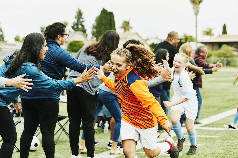 Young female soccer goalie high fiving parents on sidelines after soccer game Photograph by Thomas Barwick