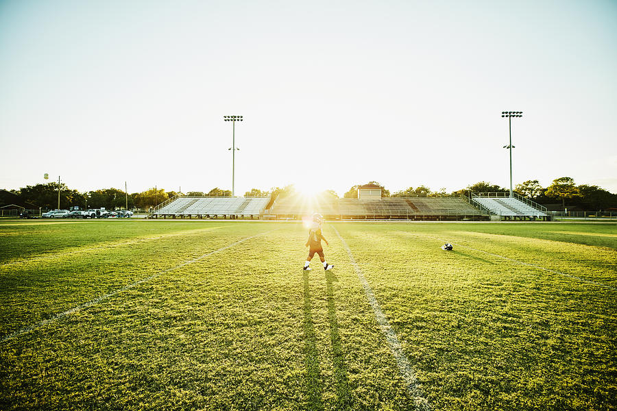 Young football player walking on football field after practice Photograph by Thomas Barwick