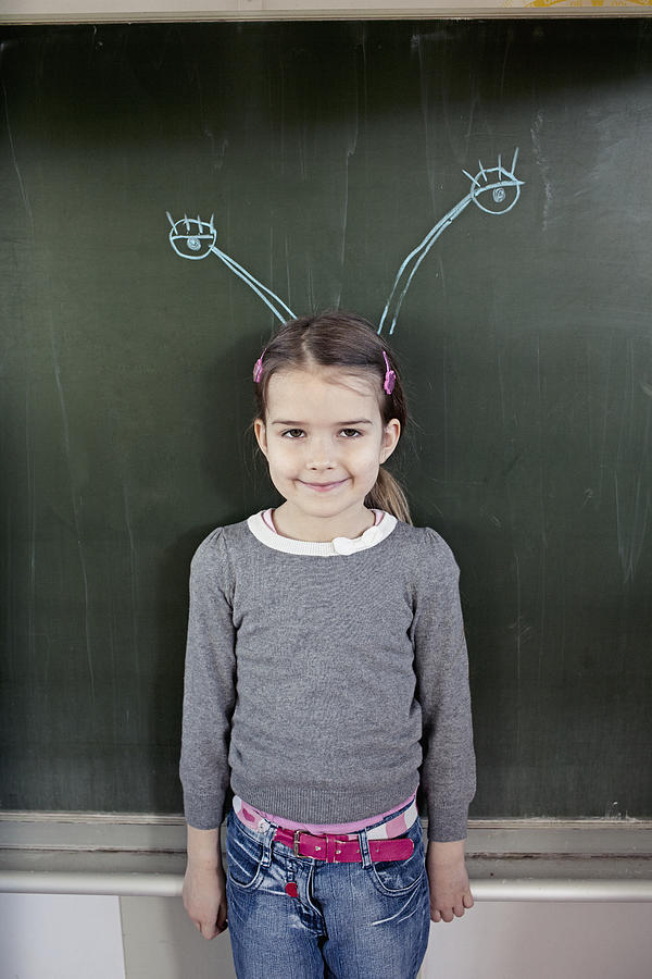 Young girl (6-7) standing in front of blackboard with insect feelers drawn on it Photograph by Oliver Rossi