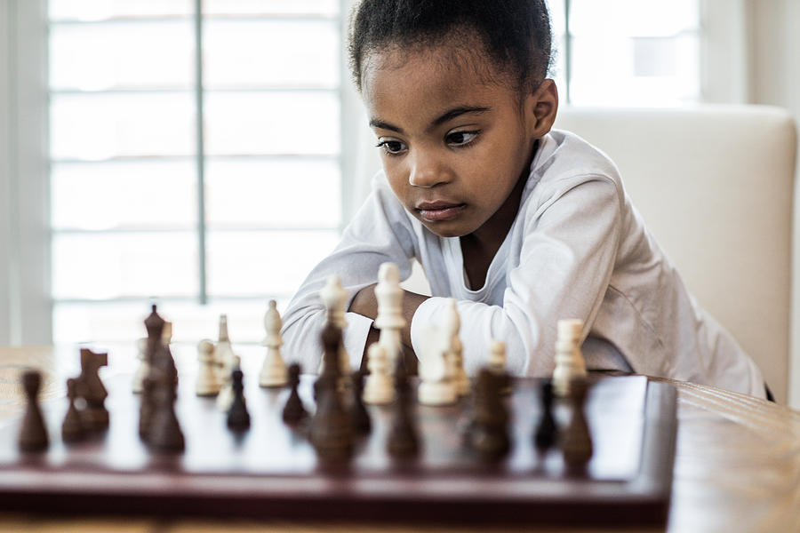Young girl (6yrs) playing chess with Photograph by MoMo Productions