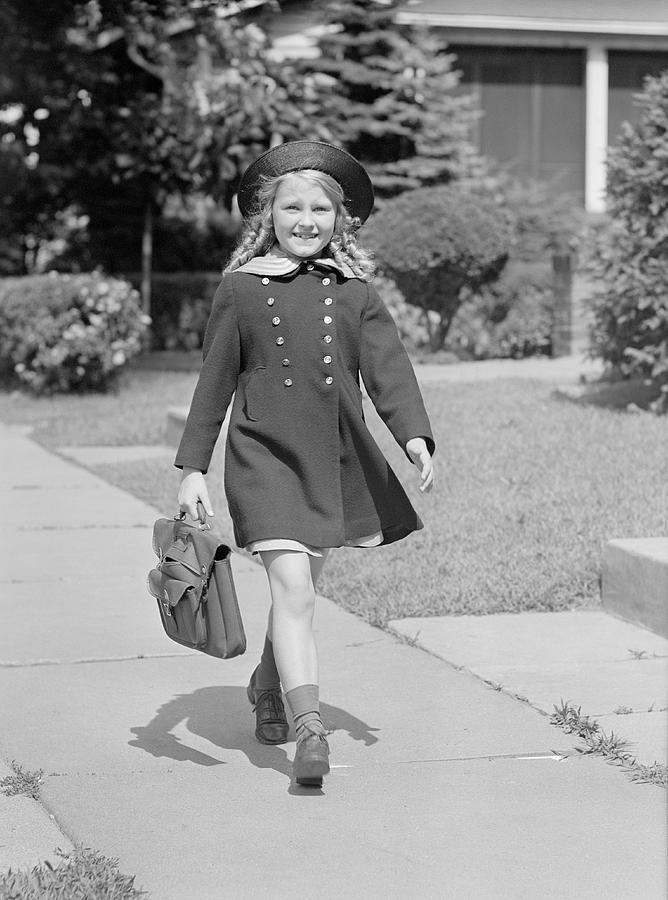 Young girl (8-9) with schoolbag on sidewalk, portrait Photograph by George Marks