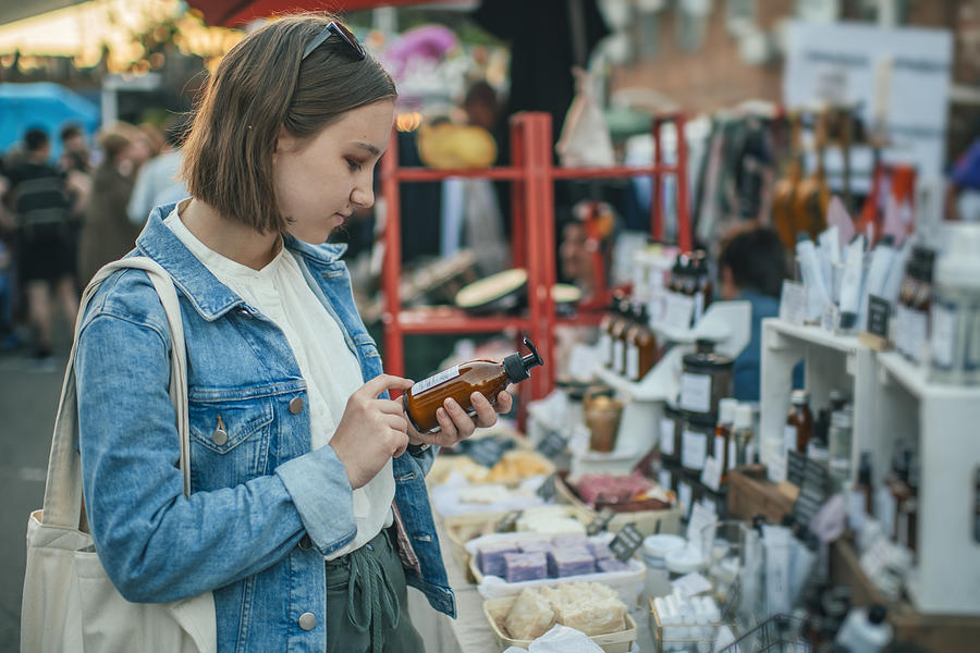 Young girl exploring organic body care goods at an open-air market with zero waste concept Photograph by ArtMarie