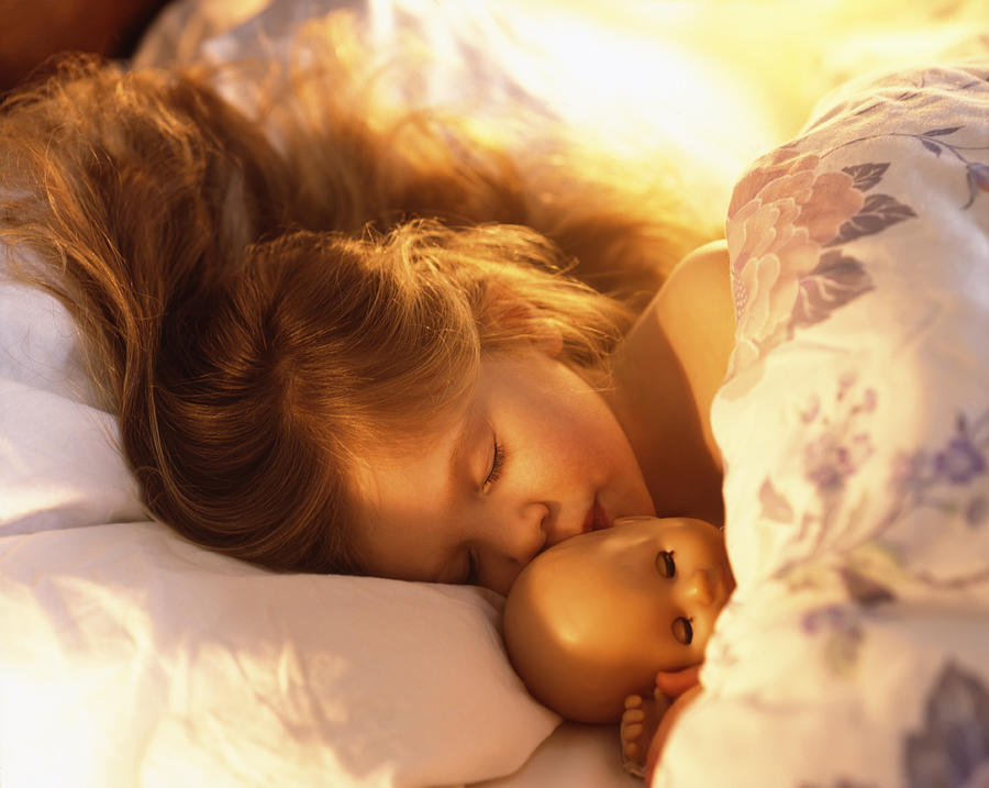 Young girl in bed asleep with doll Photograph by Peter Cade
