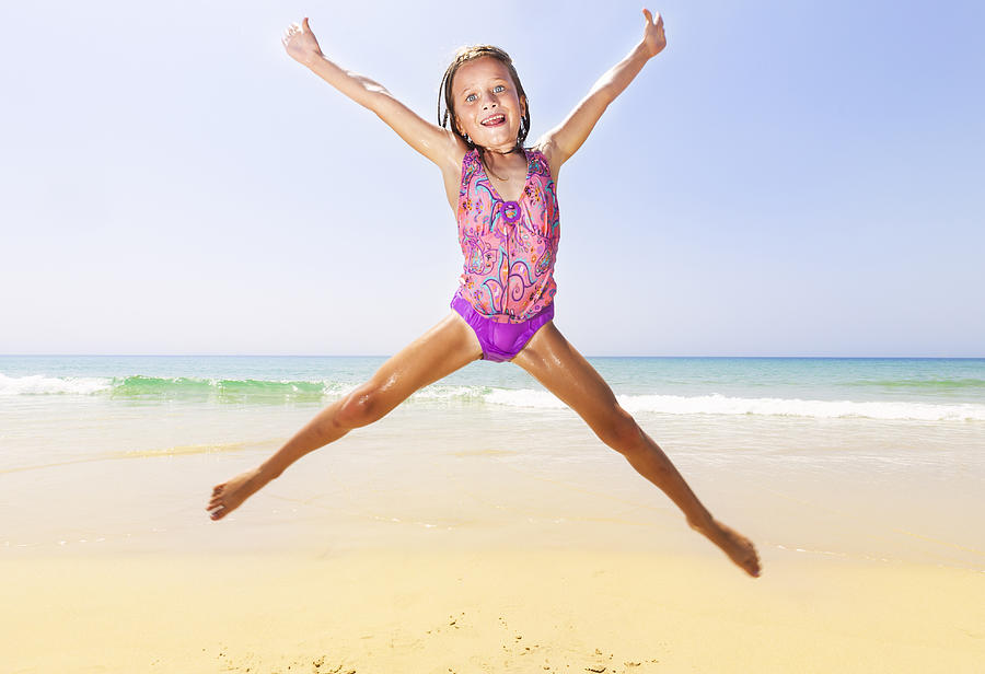 Young girl jumping at beach with arms in the air Photograph by Marcos Welsh