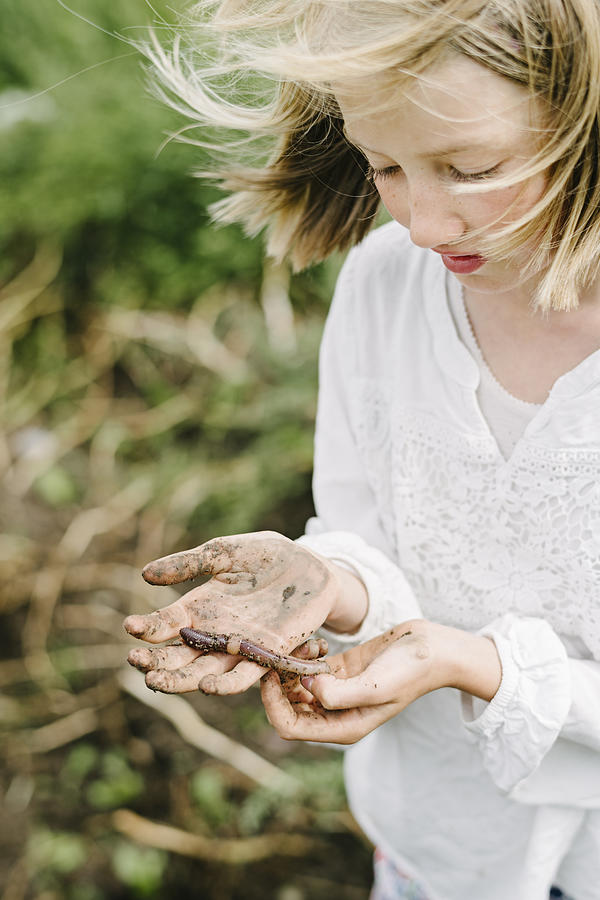 Young Girl Learning and Playing With An Earthworms in Her Kitchen Garden. Photograph by ClarkandCompany