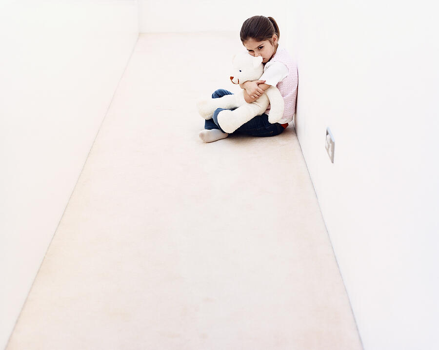 Young Girl Sitting Alone in a Corridor and Hugging a Cuddly Toy Photograph by Dylan Ellis
