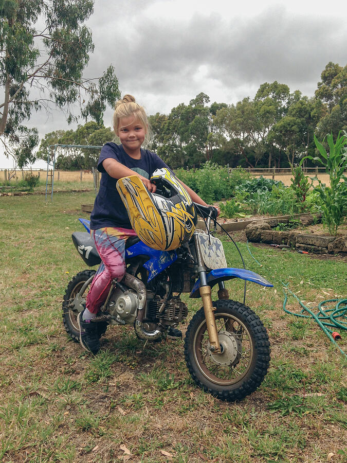 Young girl sitting on small motorcycle outside Photograph by Jodie Griggs