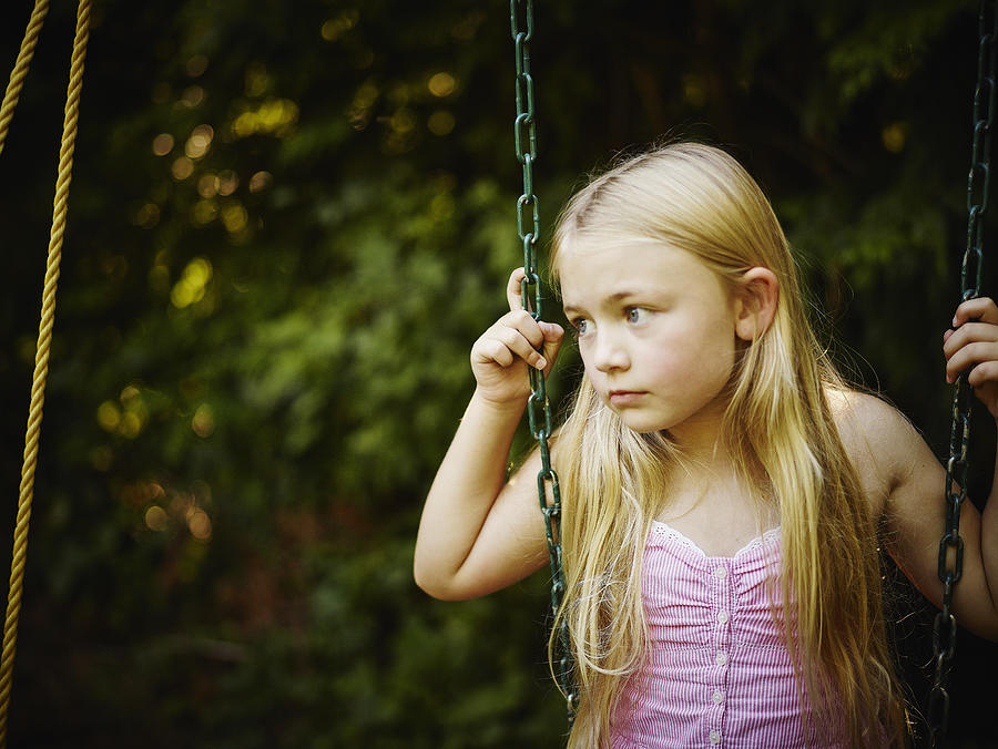 Young girl sitting on swing looking out Photograph by Thomas Barwick