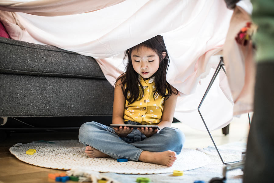 Young girl using tablet in homemade fort at home Photograph by MoMo Productions