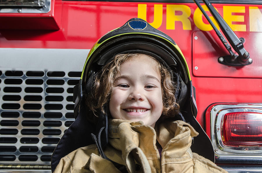Young girl wearing fireman coat and helmet Photograph by Marc Dufresne