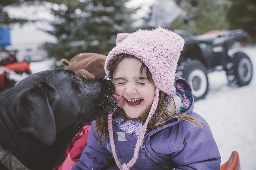 Young girl with dog in snowy landscape, dog licking girls face Photograph by Jenn Austin-Driver (Photography)