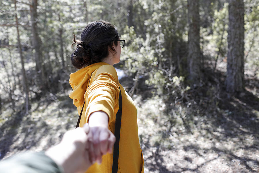 Young girl with yellow sweater holding hand of man in the forest Photograph by Westend61