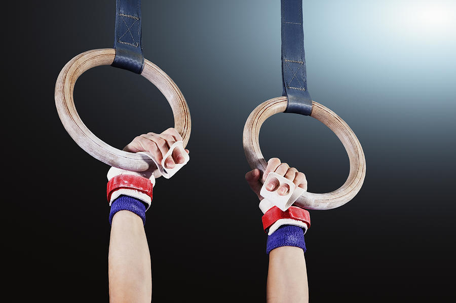 Young gymnast hanging from rings Photograph by Robert Decelis