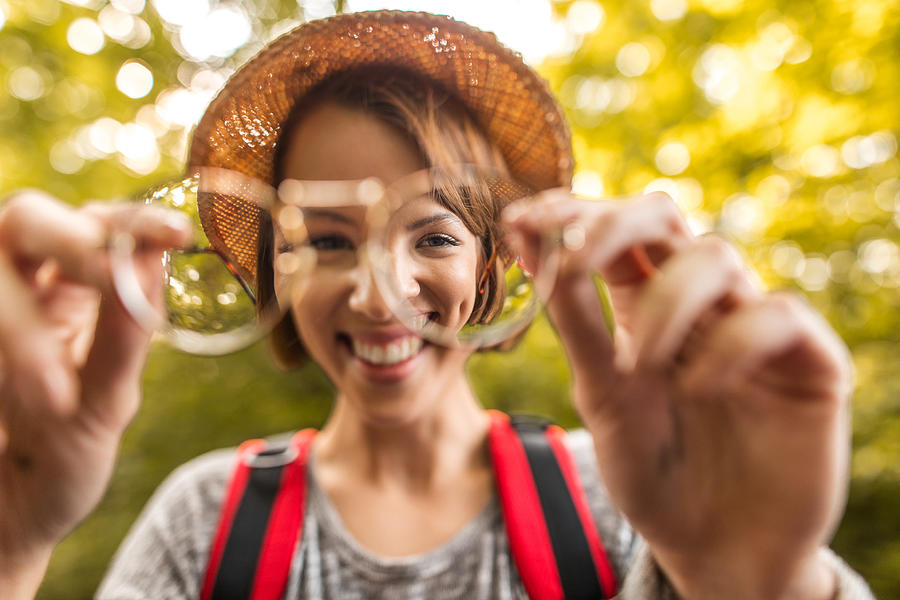 Young happy woman seen through eyeglasses lens in nature. Photograph by Skynesher